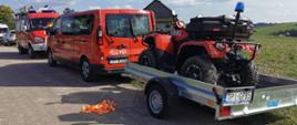 Strażacy ratownicy przygotowujący się do poszukiwań. Pojazd quad na przyczepie podpiętej do samochodu strażackiego.
