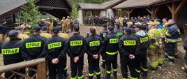 Ćwiczenia pod kryptonimem "KORYCINY 25' - strażacy stoją w okręgu, są z nimi kierownicy ćwiczeń i przedstawiciele Nadleśnictwa Rudka