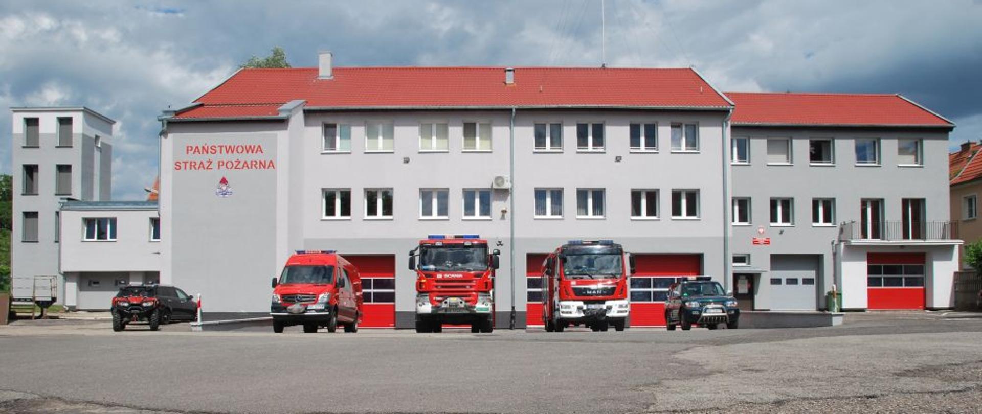 Widoczna od frontu jednostka ratowniczo gaśnicza nr 2 w Elblągu. Przed bramami garażowymi stoją wystawione pojazdy pożarnicze.