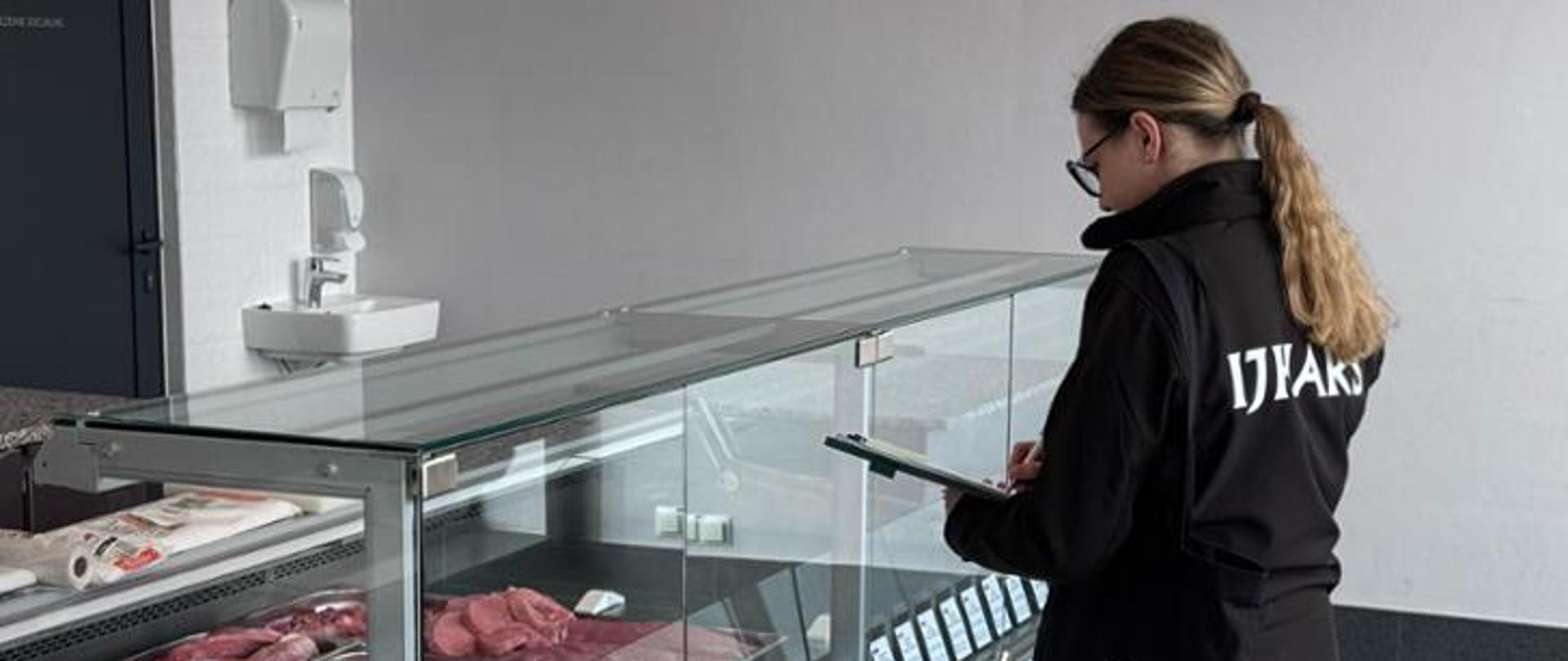 Pracownik Inspekcji podczas kontroli mięsa w sklepie.