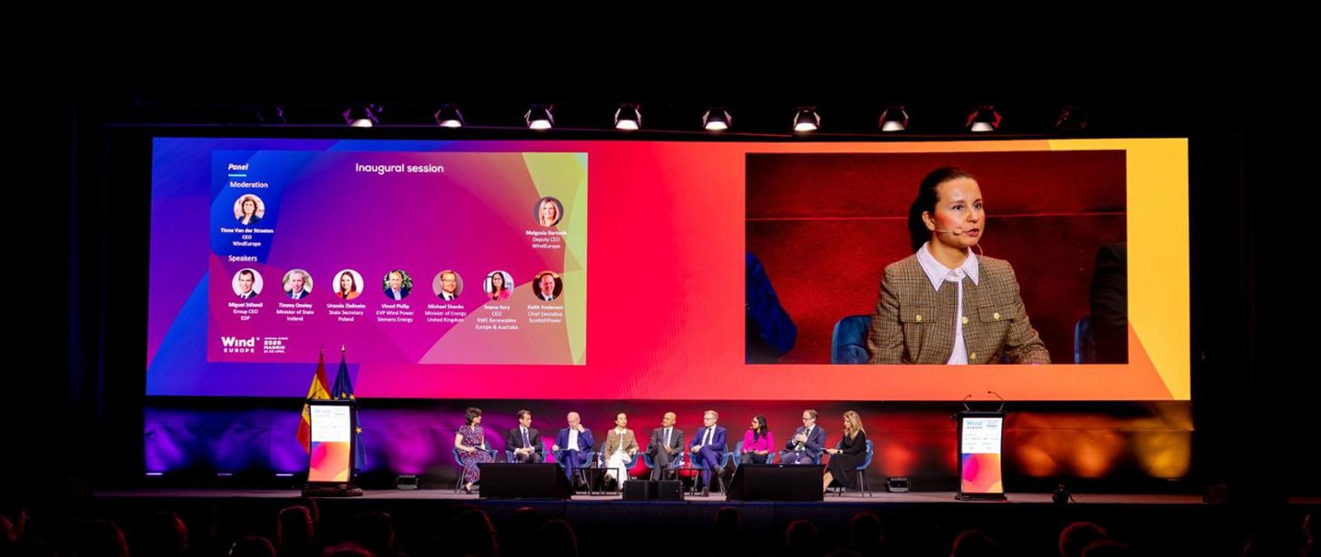 Deputy Minister of Climate and Environment Urszula Zielińska at the WindEurope 2026 conference. The photo shows a stage with nine people seated on chairs engaged in a discussion, including the Deputy Minister. Behind them, there is a screen displaying a close-up of the Deputy Minister speaking.