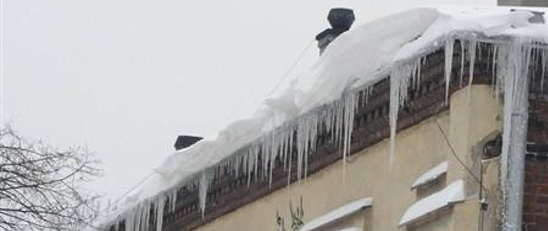 foto przedstawia oblodzoną krawędź dachu, nawisy śnieżne