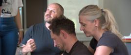 Instruktor demonstruje sposób podnoszenia i stabilnego podtrzymywania osoby w pozycji siedzącej podczas ćwiczeń szkoleniowych.