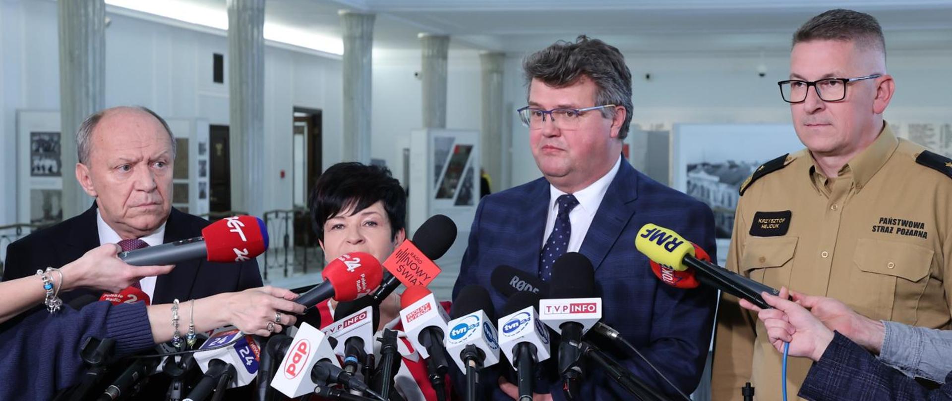 Na zdjęciu minister wraz z komendantem głównym oraz innymi osobami udzielają wywiadu