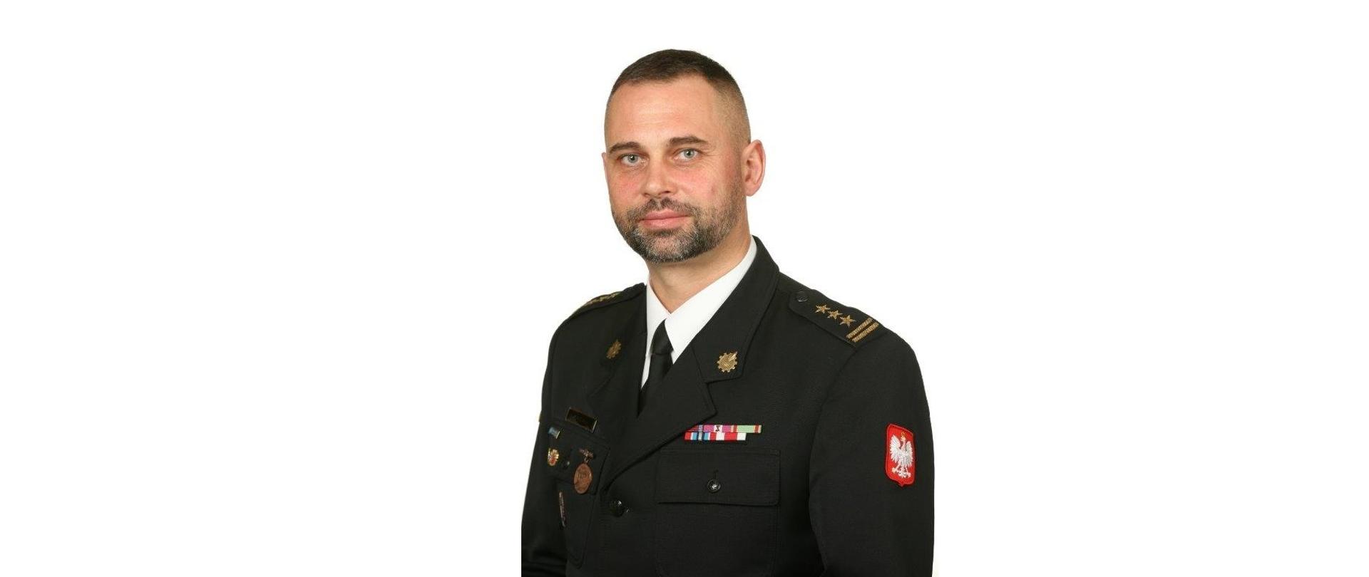 Zdjęcie portretowe zastępcy komendanta st. bryg. Paweł Kaliński na jasnym tle w mundurze galowym