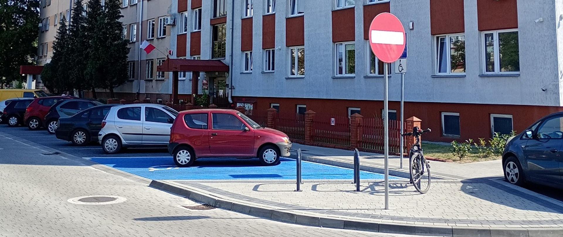 Wejście do budynku. Przed budynkiem miejsce parkingowe dla osób z niepełną sprawnością.