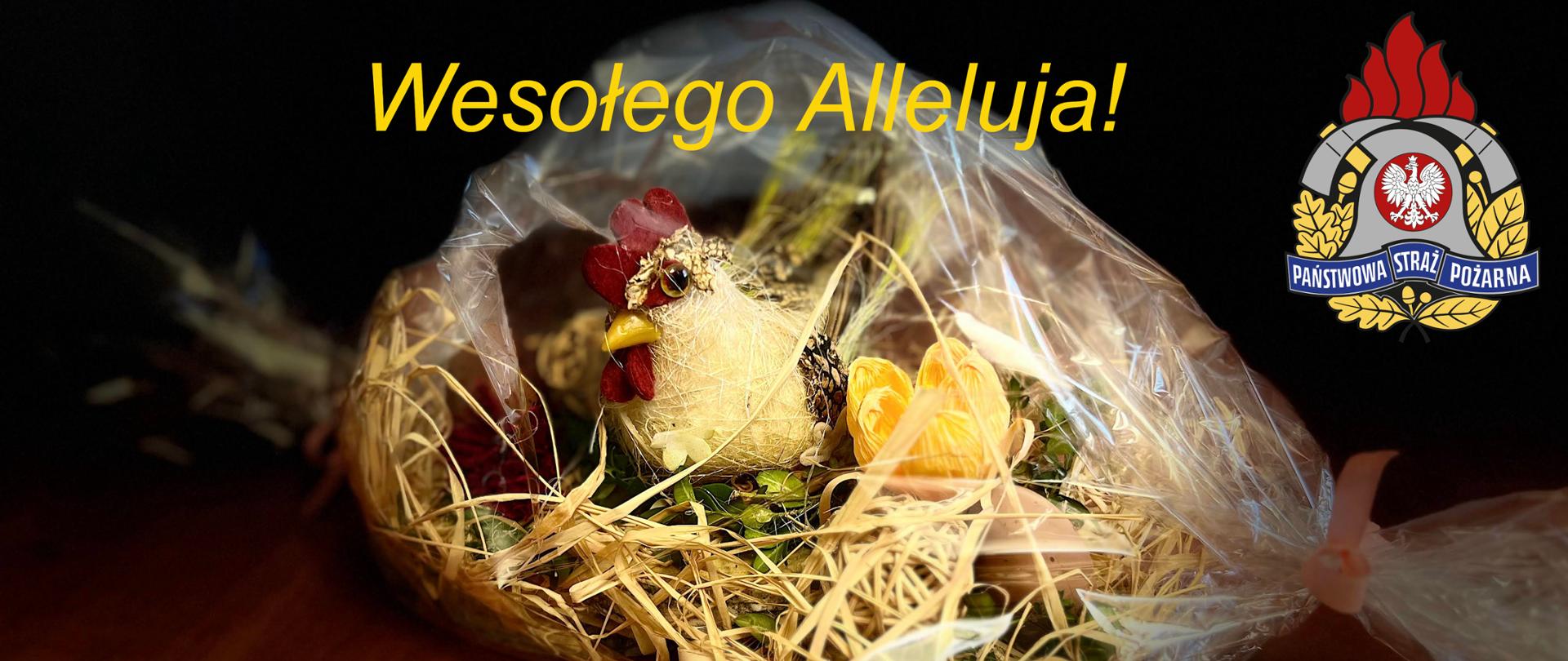 Zdjęcie ozdobnego świątecznego gniazda z kurą, pisanką, wiosennymi kwiatami, zapakowanego w folii leżącego na stole. Nad ozdobą żółty napis Wesołego Alleluja. W górnym prawym rogu logotyp Państwowej Straży Pożarnej .