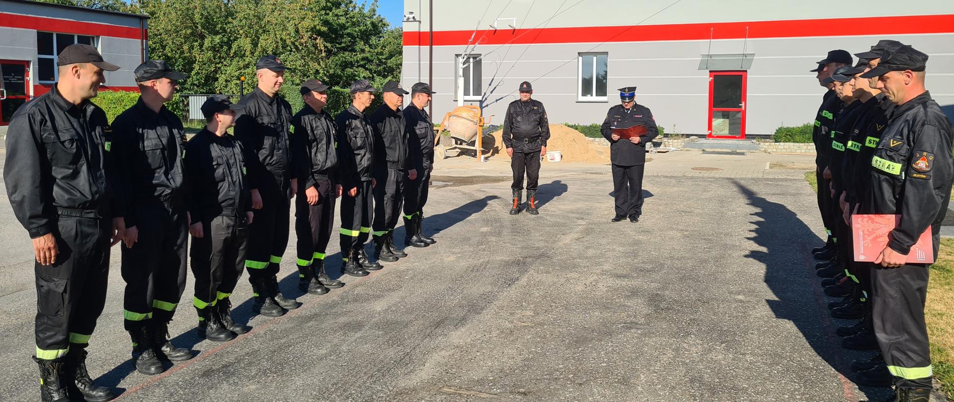 Komendant Powiatowy PSP w Złotowie mł. kpt. Tomasz Lewandowski podczas podczas czytania rozkazu. W tle Z-ca d-cy JRG st. kpt. Przemysław Jasiłek i strażacy JRG zmiany przyjmującej i zdającej służbę. 