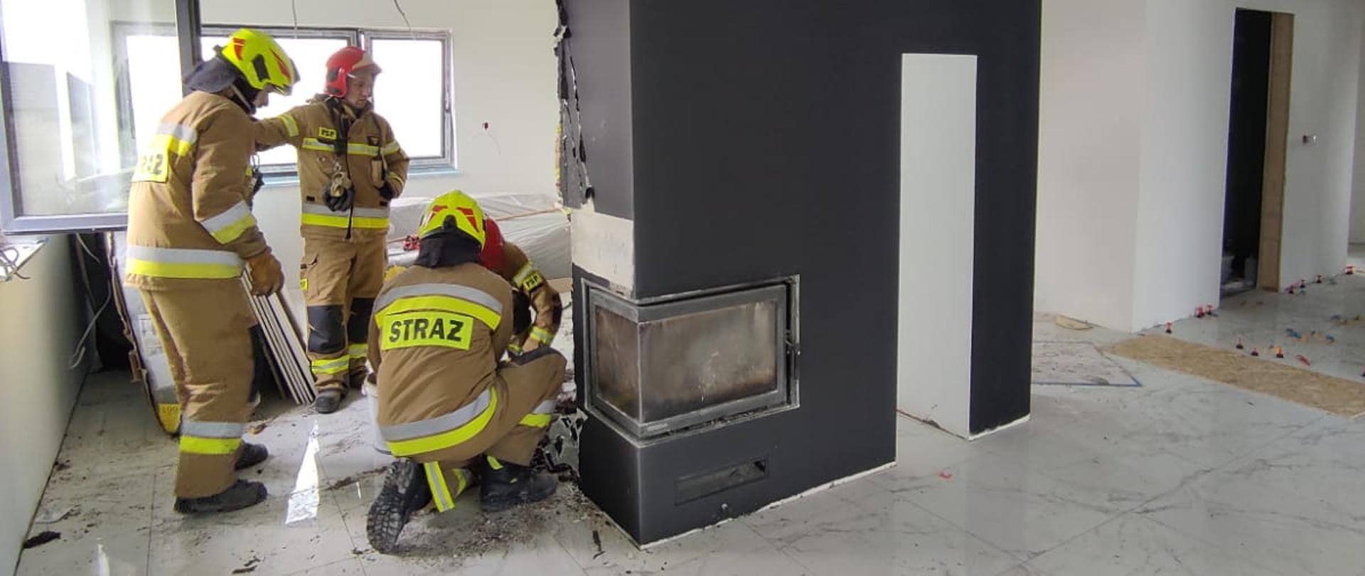 Strażacy pracują przy pożarze obudowy kominka