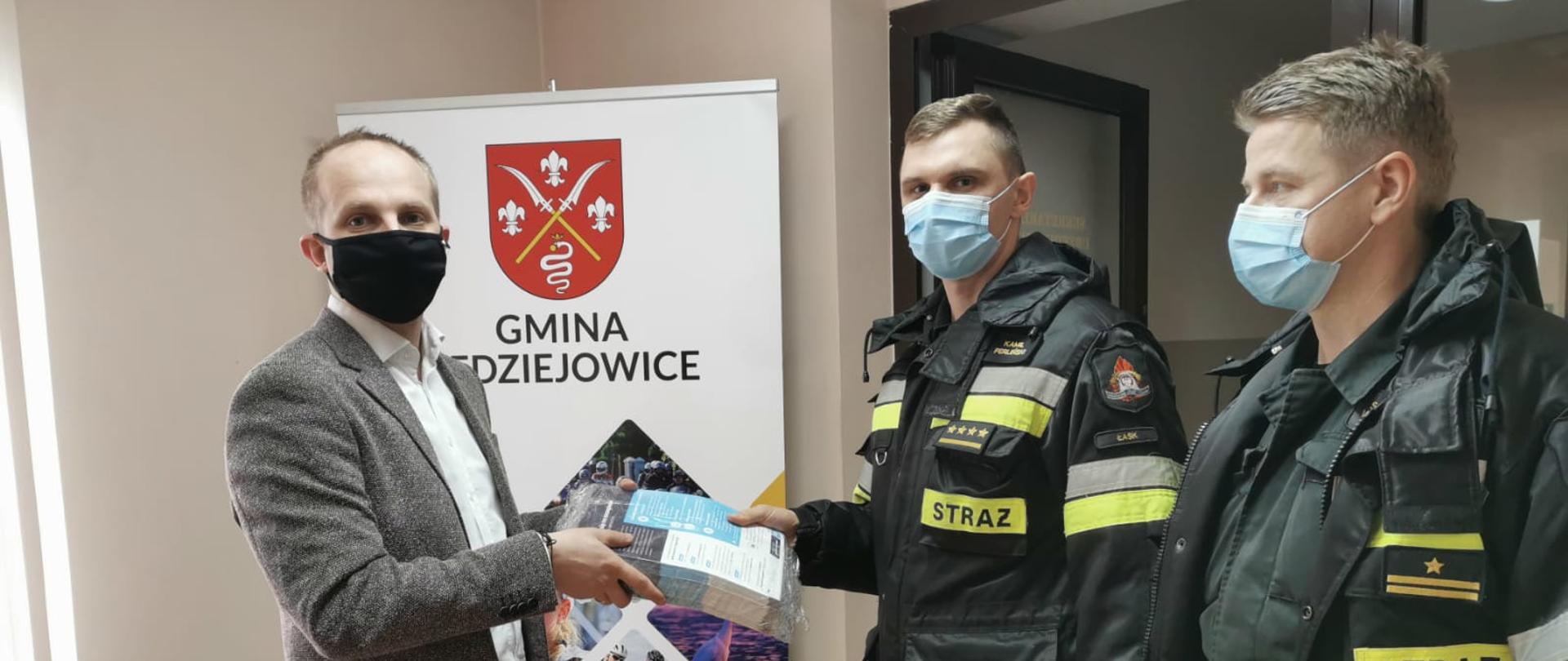 Zdjęcie przedstawia przekazanie ulotek przez strażaka dwóch strażaków, wójtowi gminy widawa.