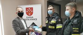 Zdjęcie przedstawia przekazanie ulotek przez strażaków, Wójtowi Gminy Sędziejowice