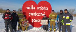 strażacy stoją przy dużym sercu WOŚP