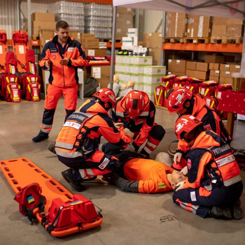 Strażacy w pełnym stroju ćwiczą pierwszą pomoc na fantomie