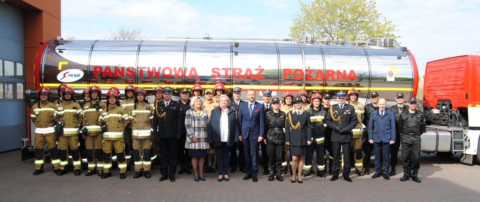 Zdjęcie grupowe na tle cysterny z napisem PAŃSTWOWA STRAŻ POŻARNA