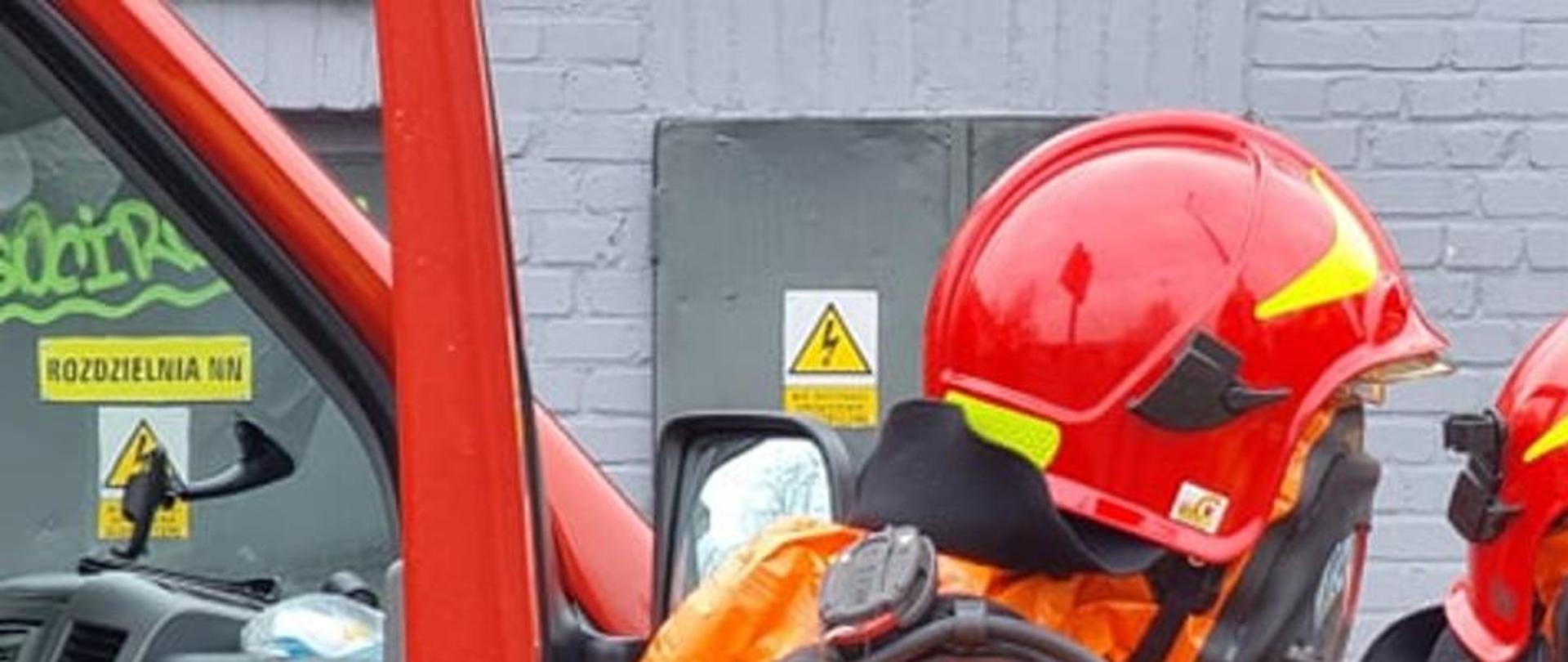 Strażacy ubrani w pomarańczowe ubrania zabezpieczające w tle budynek