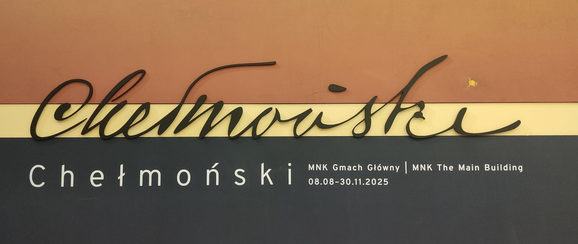 Ścienna instalacja zapowiadająca wystawę „Chełmoński” w Muzeum Narodowym w Krakowie. Na górze widnieje duży, czarny, kaligraficzny napis „Chełmoński”, a poniżej biały napis drukowanymi literami: „Chełmoński | MNK Gmach Główny”. Tło tworzą poziome pasy w odcieniach brązu, żółci i granatu