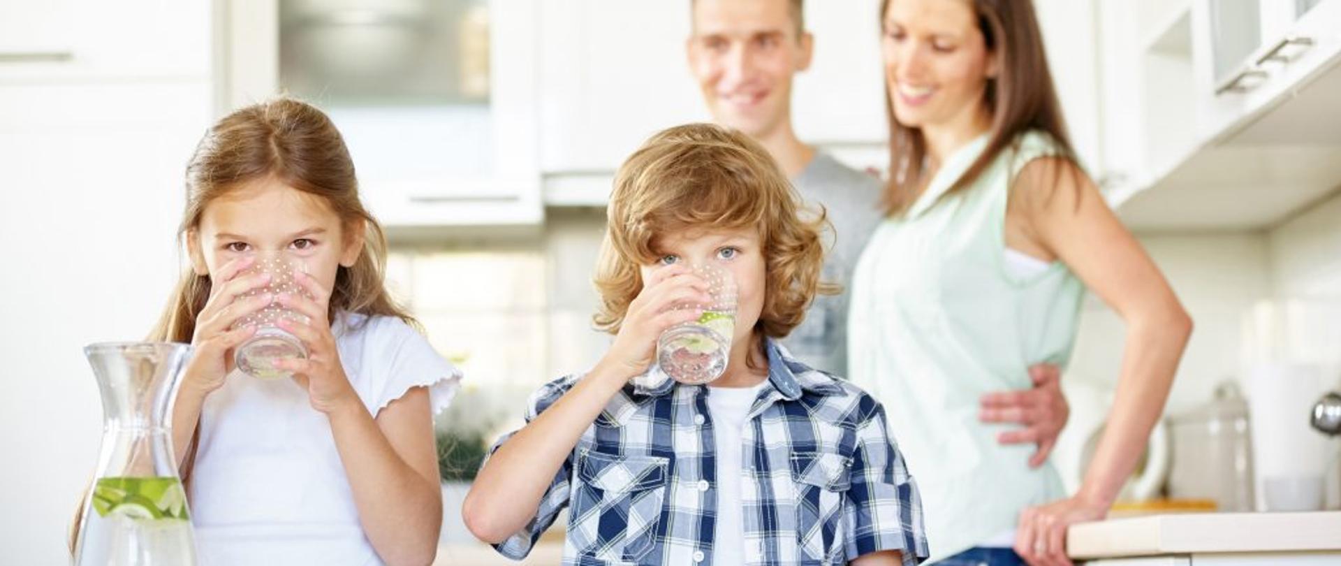 rodzina 4 osoby 2 dzieci pije wodę ze szklanek