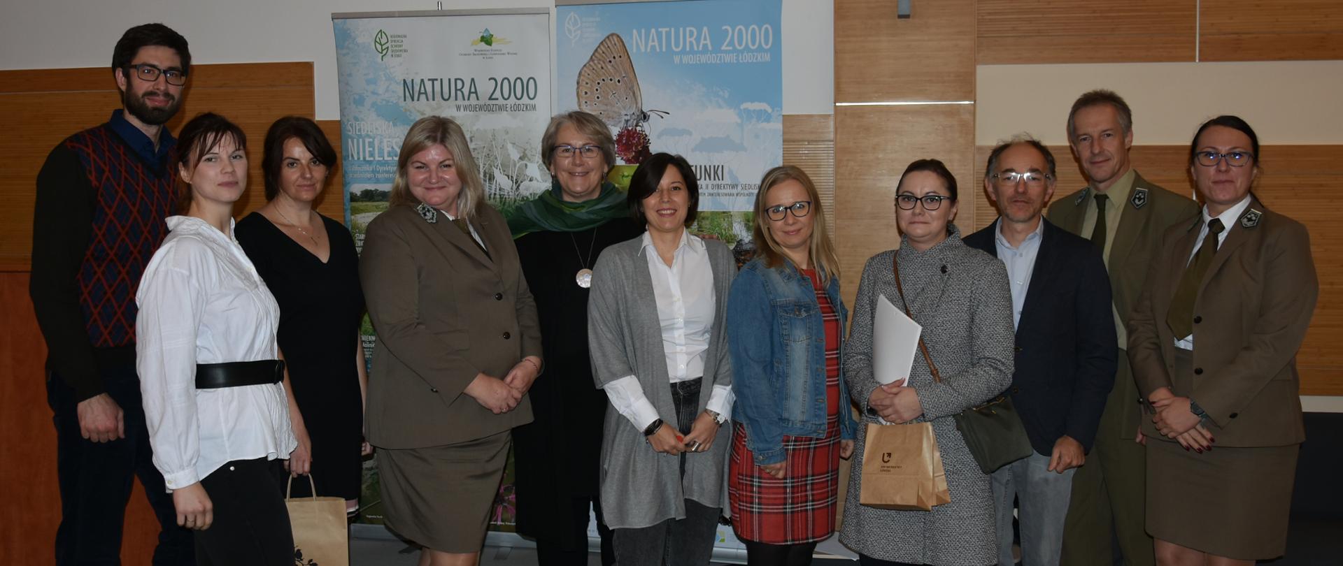 11 osób patrzy z lekkim uśmiechem w obiektyw aparatu 