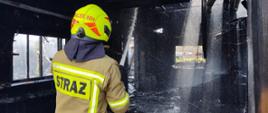 Strażak prądem rozproszonym dogasza pożar.