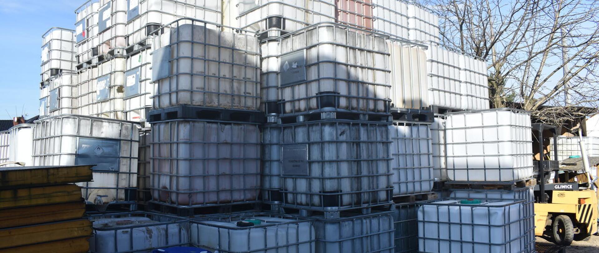 Plastikowe pojemniki o pojemności 1000 l stoją jedne na drugich nawet po cztery w kolumnie na nieutwardzonym podłożu.