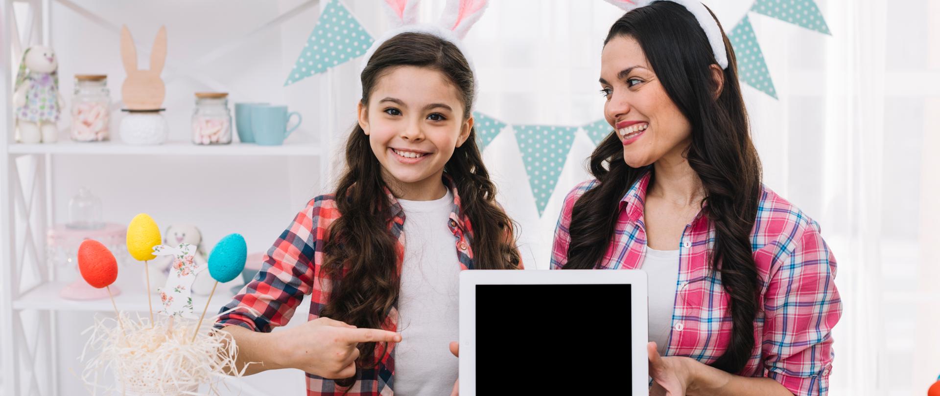Matka z córką w wielkanocnej aranżacji córka-wskazuje-palcem tablet, który trzyma mama
