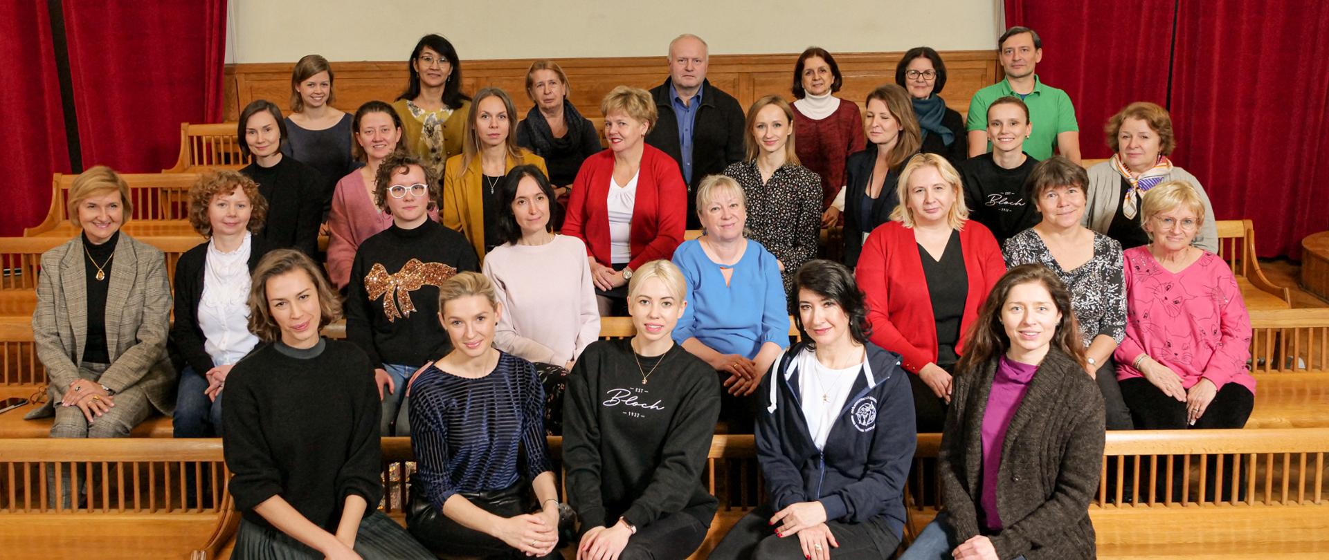 Zdjęcie przedstawia grono pedagogiczne szkoły, nauczyciele siedzą w auli.