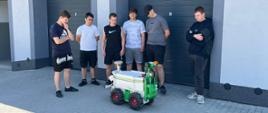 Grupa uczniów obserwuje autonomiczny robot rolniczy podczas prezentacji na placu szkoleniowym.