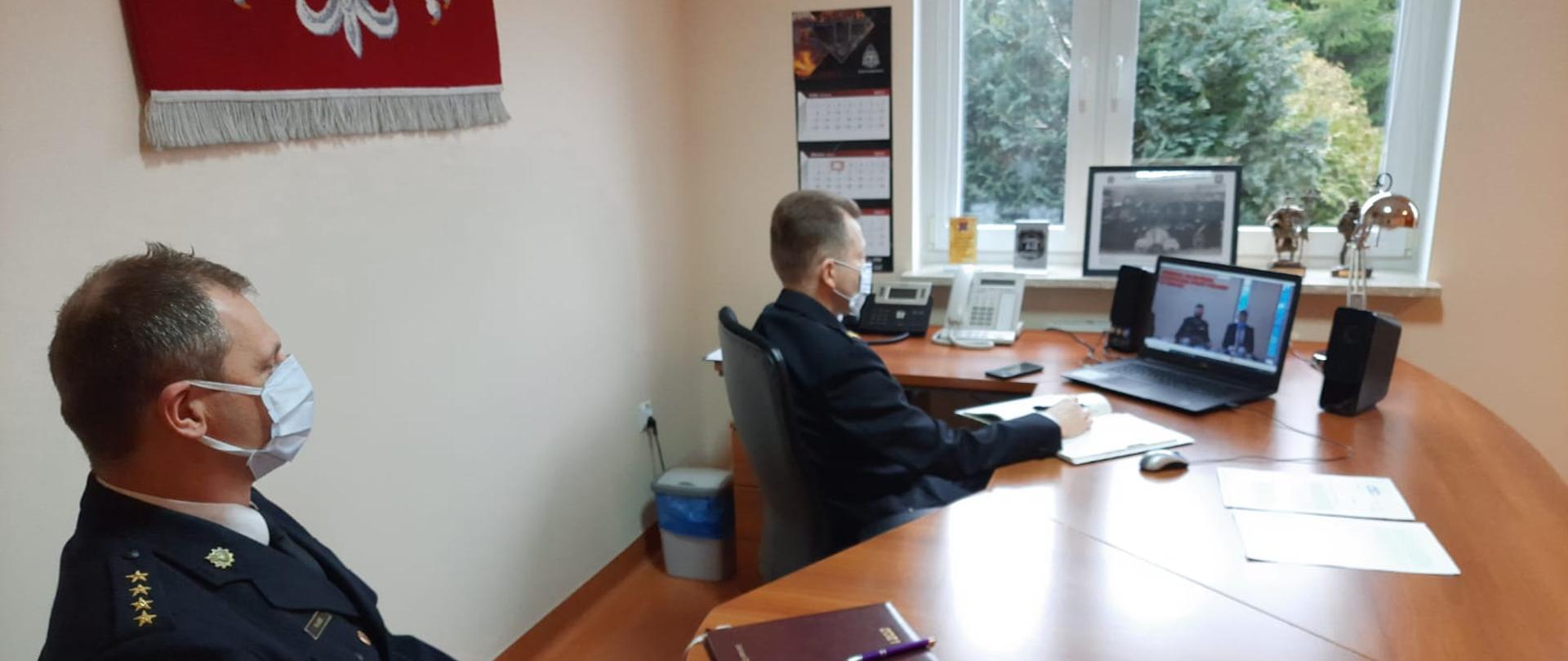 Zdjęcie wykonano w budynku Komendy Powiatowej Państwowej Straży Pożarnej w Sępólnie Krajeńskim w gabinecie Komendanta Powiatowego Państwowej Straży Pożarnej st. bryg. mgr inż. Macieja Suchomskiego podczas telekonferencji. Na pierwszym planie widać siedzącego st. kpt. mgr inż. Roberta Lissa, a na dalszym planie Komendanta Powiatowego Państwowej Straży Pożarnej st. bryg. mgr inż. Macieja Suchomskiego. 