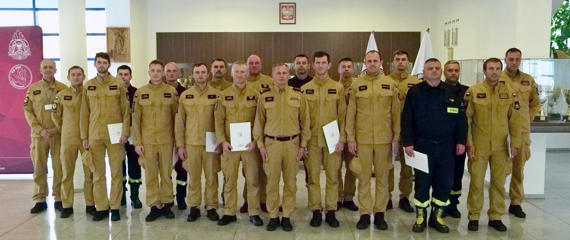 Pamiątkowe zdjęcie grupowe funkcjonariuszy PSP, będących uczestnikami szkolenia dla kierowców pojazdów uprzywilejowanych (16 osób) w towarzystwie Zastępcy Komendanta Centralnej Szkoły PSP oraz trzech funkcjonariuszy CS PSP