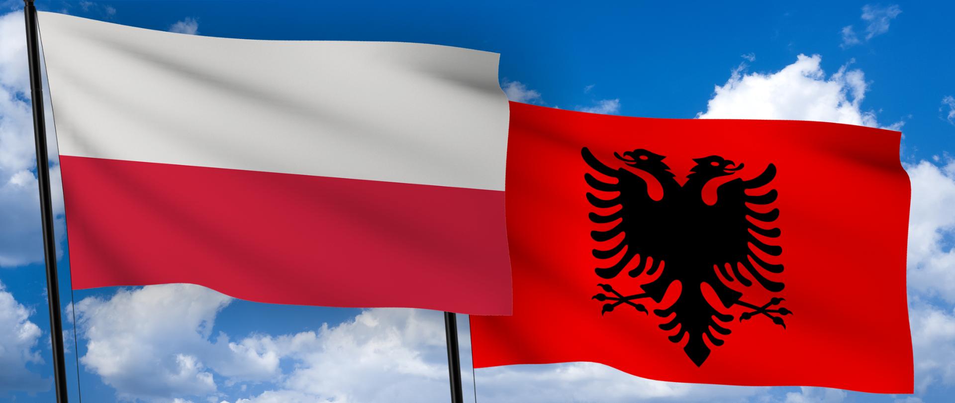 Flagi Polski i Albanii. W tle błękitne niebo i jasne chmury.