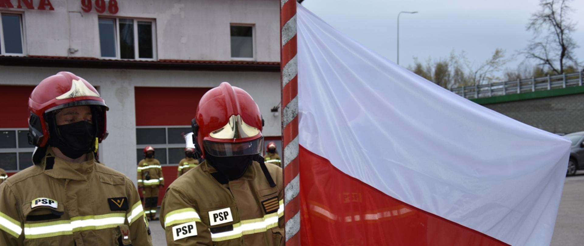 Strażacy przypinają flagę do masztu
