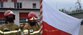 Strażacy przypinają flagę do masztu. 