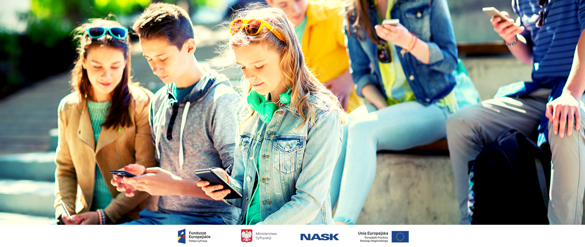 Kilkoro nastolatków siedzi na schodach, trzymają telefony i wpatrują się w ich ekrany