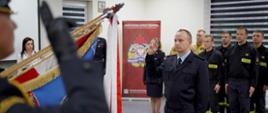 Strażak Michał Wójcik składa ślubowanie na sztandar Komedy Powiatowej Państwowej Straży Pożarnej w Brzezinach.