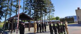 na placu wewnętrznym KP PSP Sztum stoją umundurowani funkcjonariusze podczas wciągania flagi na maszt.