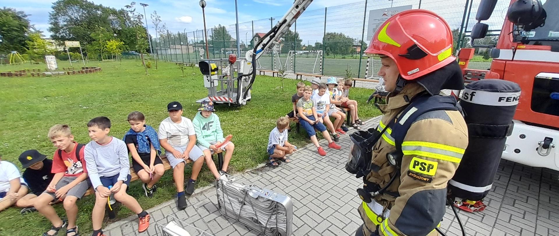 Na zdjęciu strażak w ubraniu specjalnym prezentuje sprzęt ratowniczy jakim pracują ratownicy