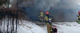 Na zdjęciu widoczni strażacy gaszący pomieszczenia garażu orz kotłowni domu mieszkalnego