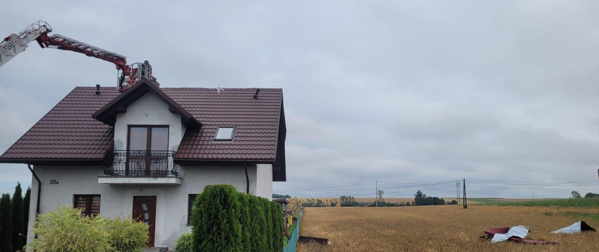 Strażacy w koszu przy uszkodzonym dachu