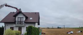 Strażacy w koszu przy uszkodzonym dachu
