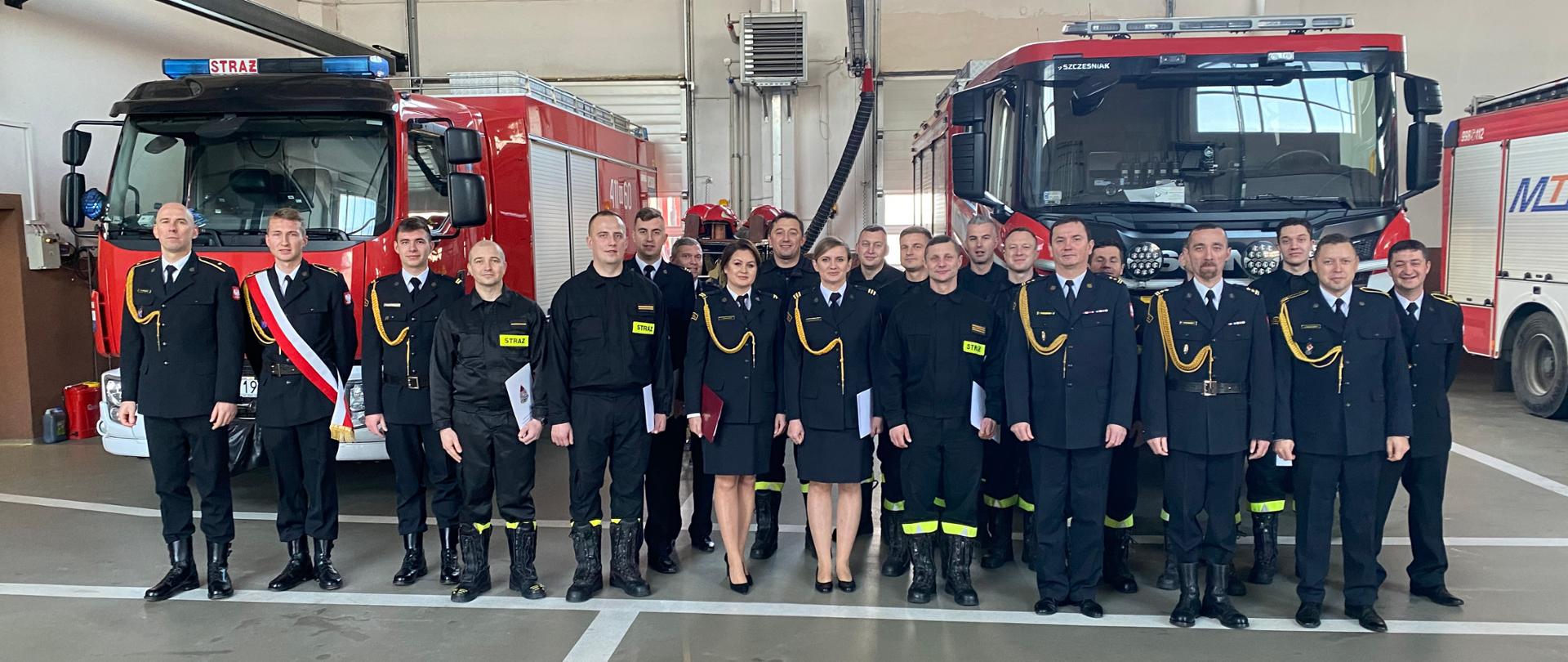 Zdjęcie grupowe funkcjonariuszy Komendy Powiatowej PSP w Ciechanowie na tle samochodów tutejszej jednostki