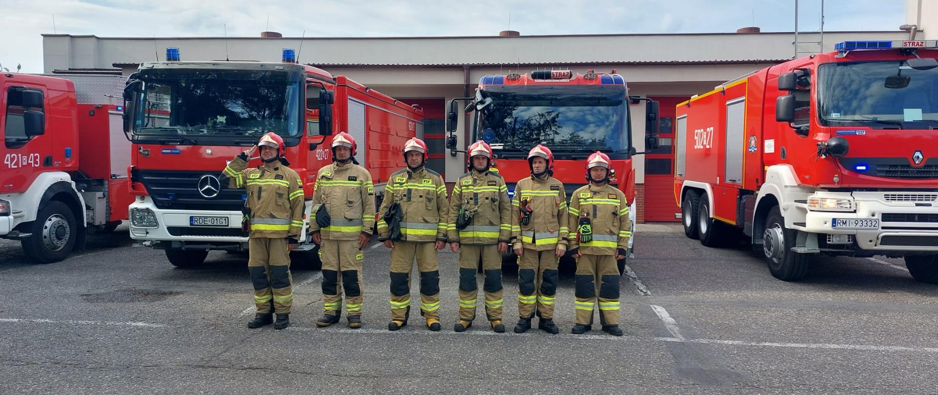 strażacy w mundurach stoją na tle samochodów 