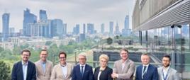 Kilka osób stoi na tarasie UTK z widokiem na panoramę Warszawy