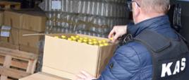 Funkcjonariusz KAS w magazynie, opakowania z butelkami z alkoholem.