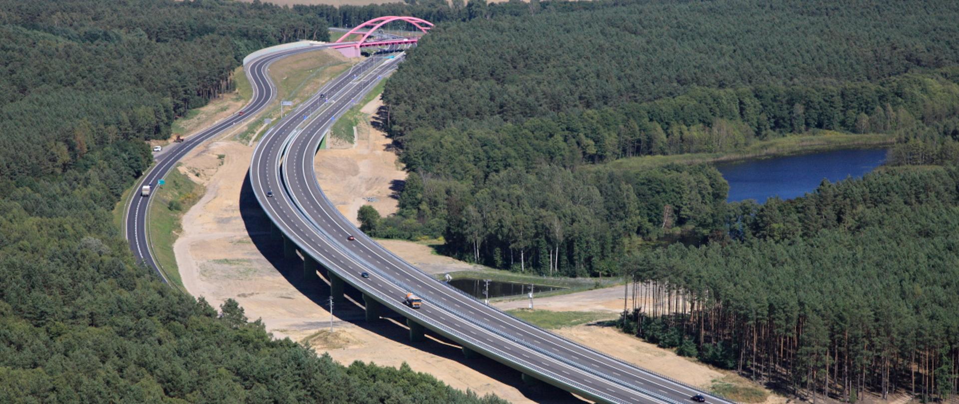 Estakada drogowa w ciągu drogi S3 rozpięta nad zbiornikiem wodnym, otoczona lasami.