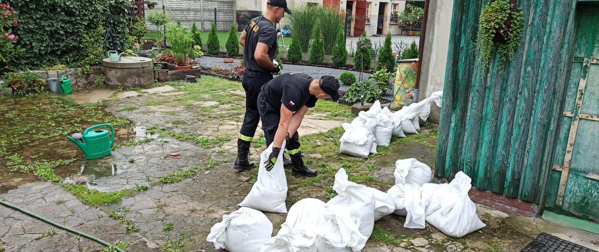 Funkcjonariusze PSP podczas układania worków z piaskiem