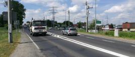 Zdjęcie jezdni na granicy Krakowa i Skawiny. Na jezdni widać poruszające się samochody w obu kierunkach.