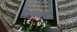 Złożony wieniec oraz zapalony znicz pod pomnikiem "W hołdzie pomorskim strażakom".