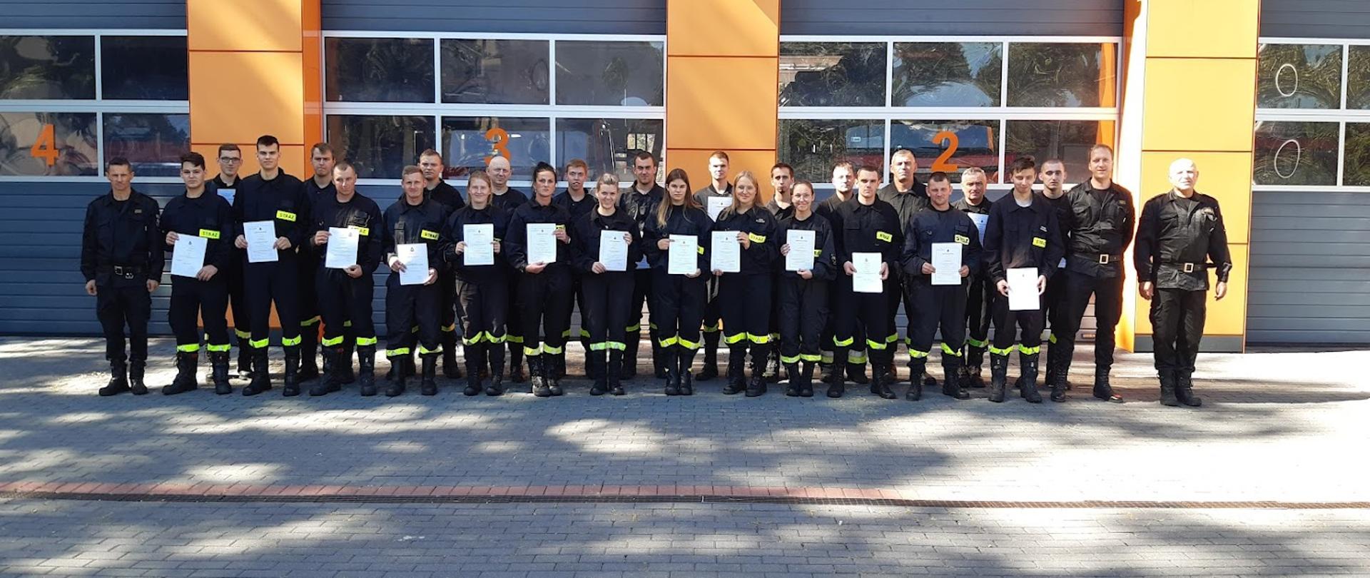 Zdjęcie grupowe wykonane na placu przed siedzibą komendy. Druhowie trzymają w rękach zaświadczenia.