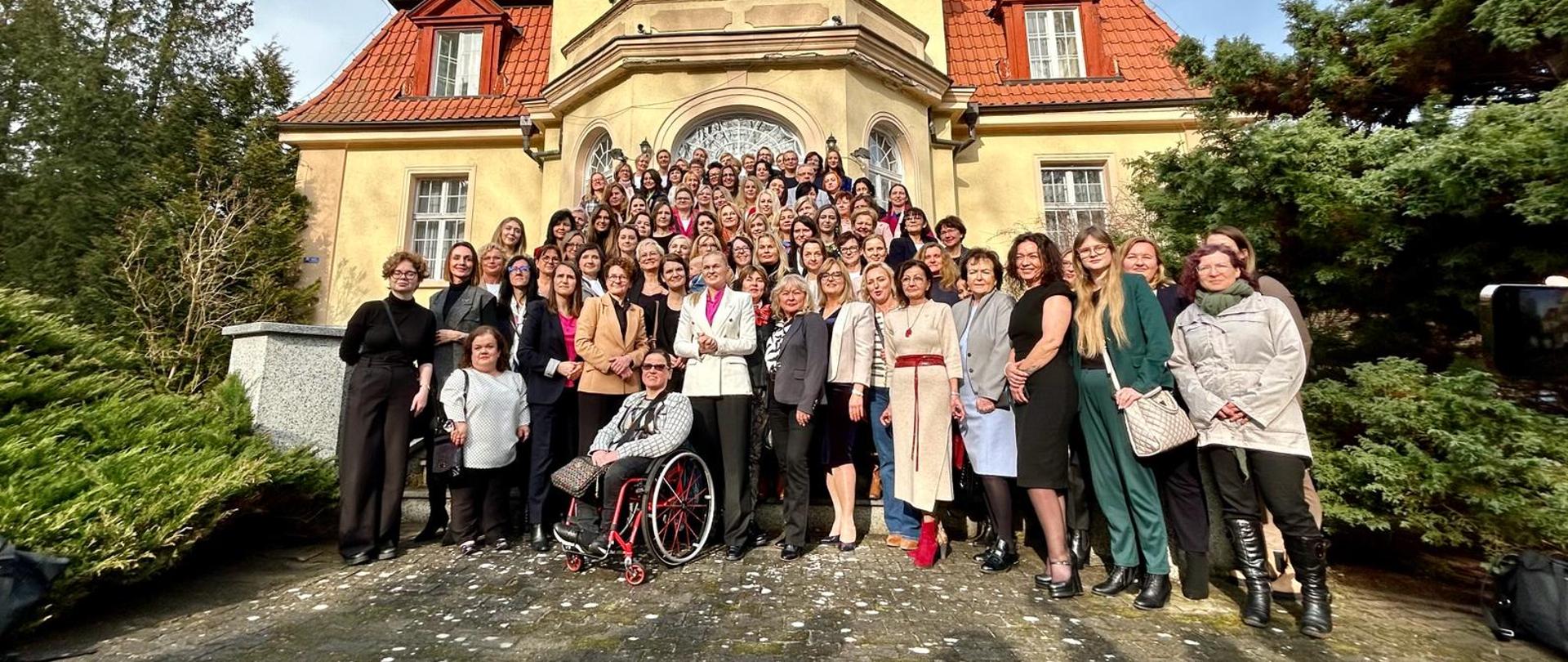 Tłum kobiet stoi przed zabytkowym budynkiem 