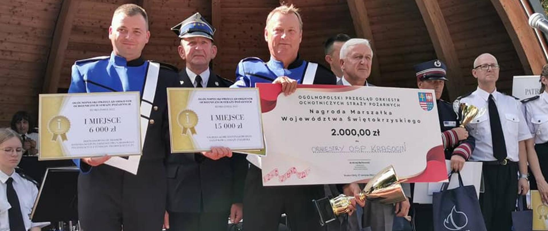 Tryumfatorzy z nagrodami. W rękach trzymają symboliczne czeki za wygranie rywalizacji.